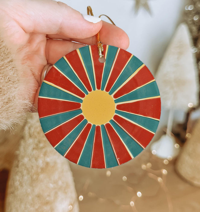 a hand holding a red, blue, and yellow ornament