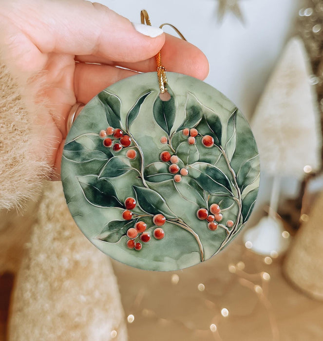a hand holding a ceramic ornament with berries on it