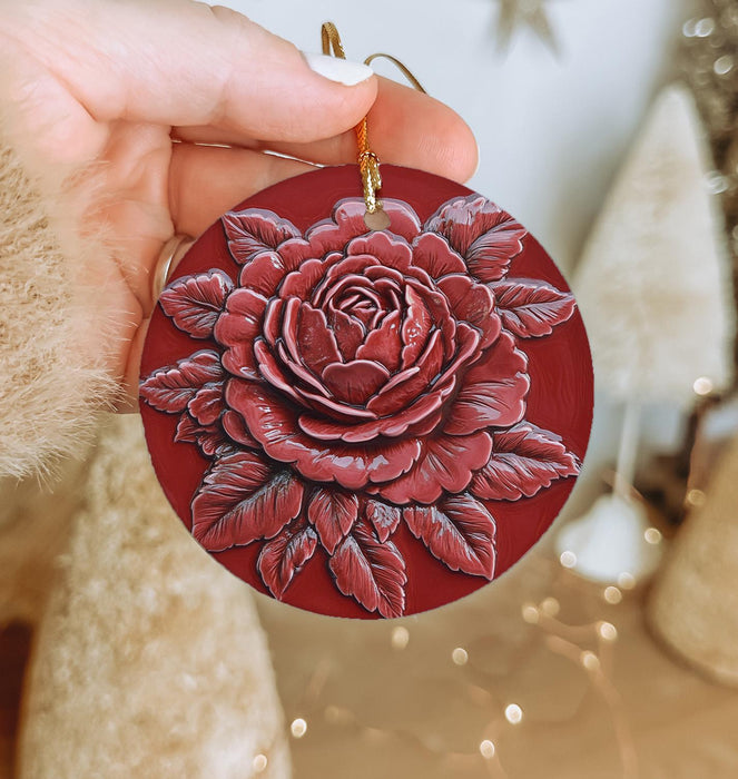 a person holding a red ornament with a rose on it