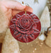 a person holding a red ornament with a rose on it