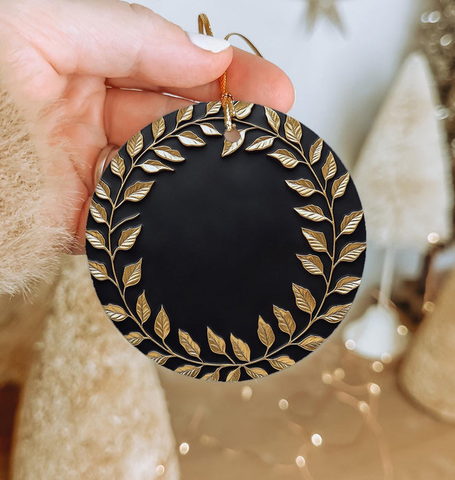 a person holding a black and gold christmas ornament