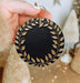 a person holding a black and gold christmas ornament
