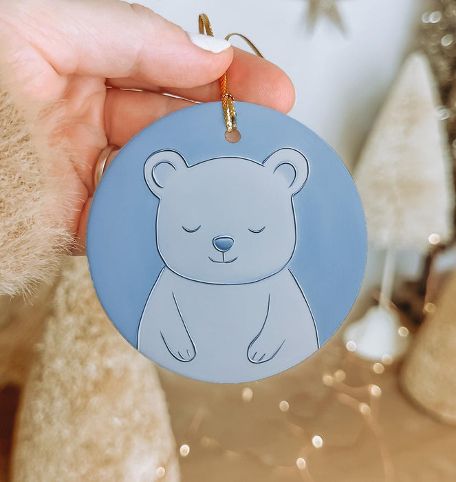 a person holding a blue ornament with a bear on it