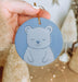 a person holding a blue ornament with a bear on it