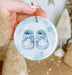 a hand holding a blue ornament with a pair of shoes on it