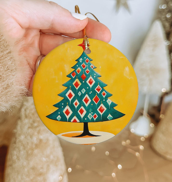 a hand holding a christmas ornament with a christmas tree on it