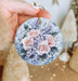 a person holding a round ornament with flowers on it