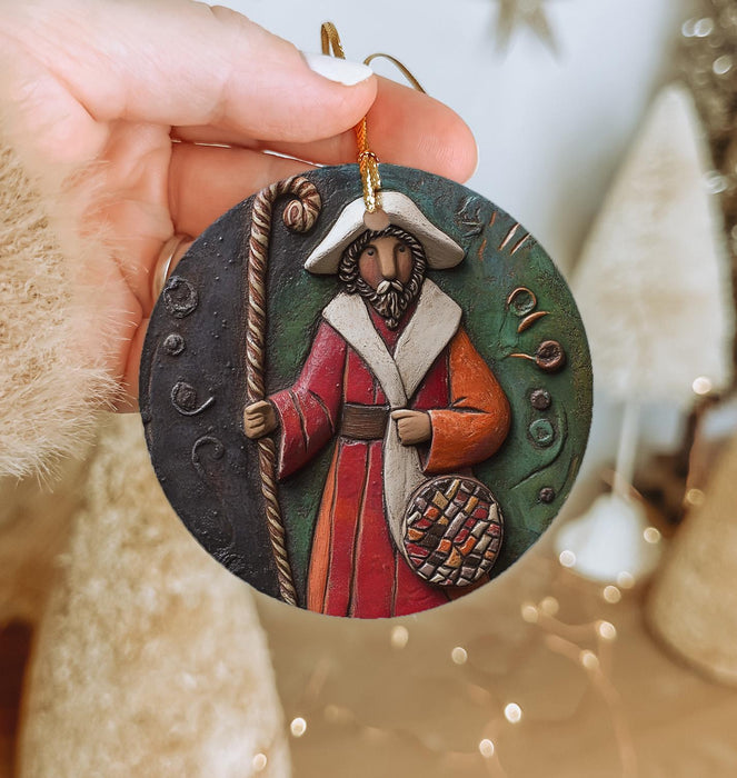 a hand holding a christmas ornament with a picture of a man