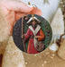 a hand holding a christmas ornament with a picture of a man