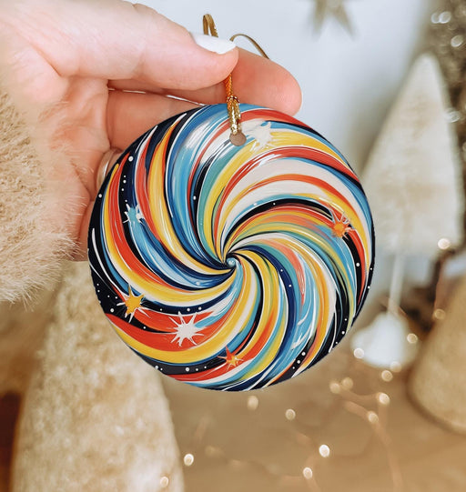 a hand holding a christmas ornament in front of a christmas tree