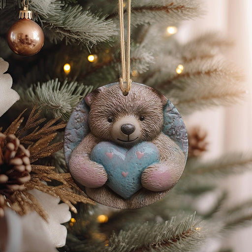 a teddy bear holding a heart ornament hanging from a christmas tree