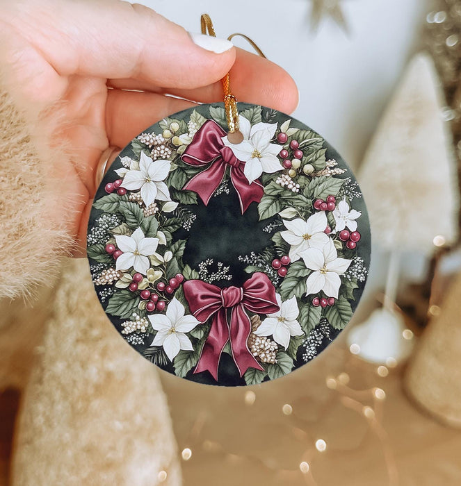 a hand holding a christmas ornament with a bow