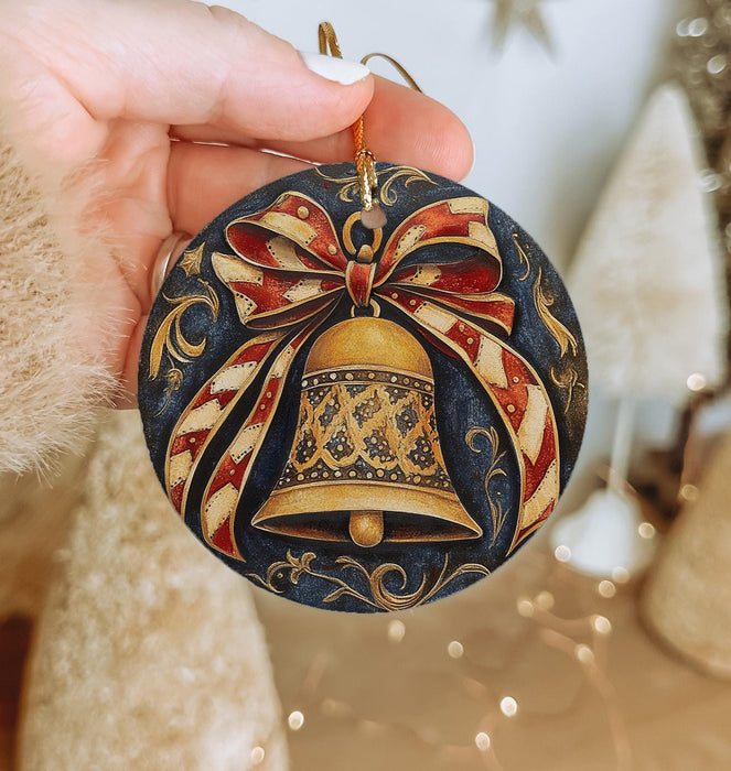 a hand holding a christmas ornament with a bell on it