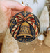 a hand holding a christmas ornament with a bell on it