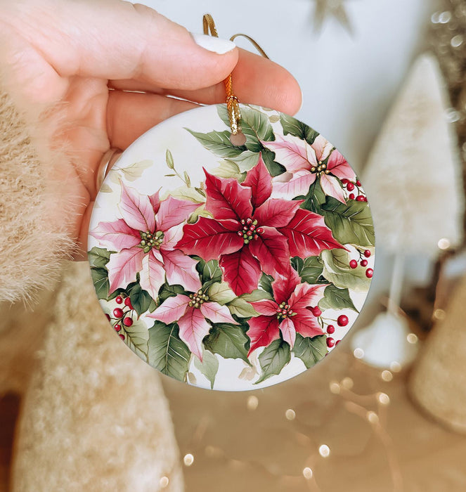 a hand holding a christmas ornament with poinsettis on it