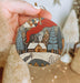 a person holding a christmas ornament in their hand