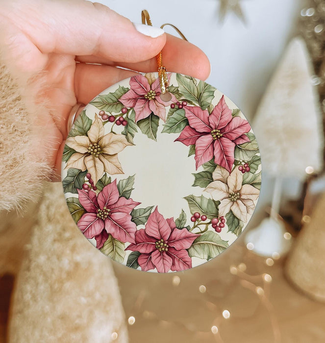 a hand holding a christmas ornament with poinsettis on it