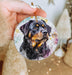 a hand holding a christmas ornament with a picture of a dog