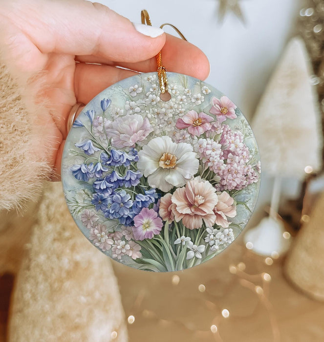 a hand holding a glass ornament with flowers on it