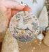 a hand holding a christmas ornament with a white horse on it