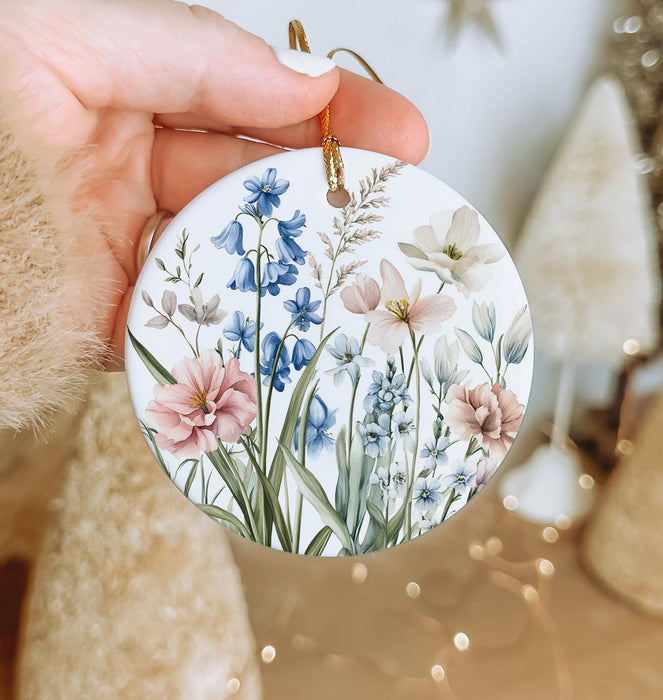 a hand holding a christmas ornament with flowers painted on it