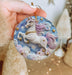 a hand holding a christmas ornament with a unicorn on it