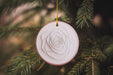 a white ornament hanging from a christmas tree