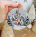 a hand holding a christmas ornament with a castle on it