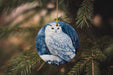 a ceramic owl ornament hanging from a pine tree