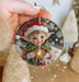 a hand holding a christmas ornament with a little elf on it
