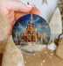 a hand holding a christmas ornament with a castle on it