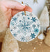 a person holding a snowflake ornament in their hand