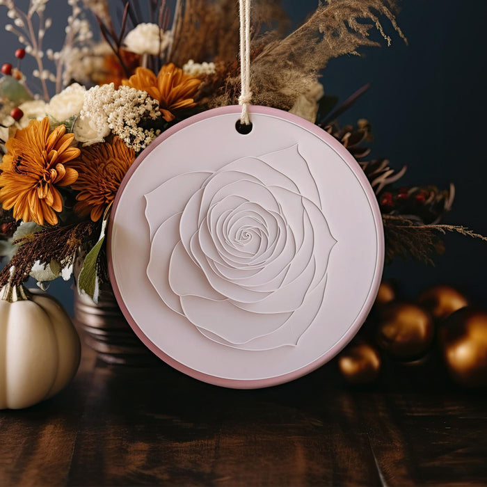 a vase with a white rose on top of a wooden table