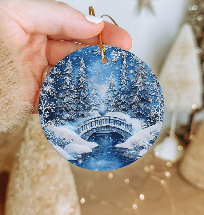 a person holding a christmas ornament with a snowy scene on it