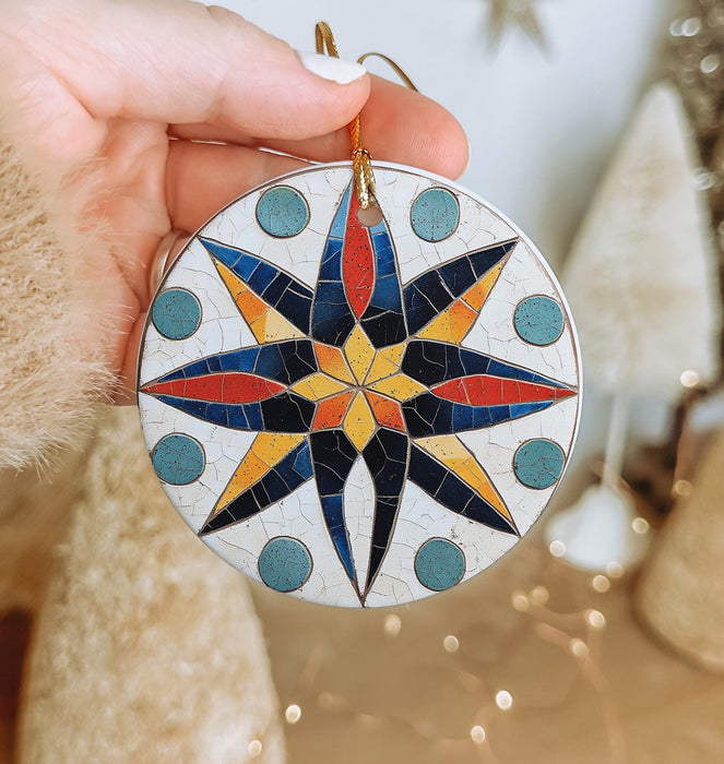 a hand holding a christmas ornament with a star on it