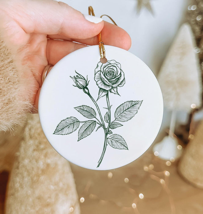 a person holding a white ornament with a rose on it