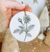 a person holding a white ornament with a rose on it
