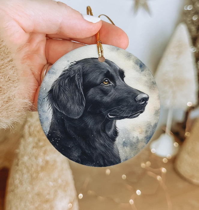 a hand holding a black dog ornament in front of a christmas tree