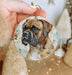 a hand holding a christmas ornament with a dog on it