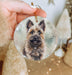 a hand holding a glass ornament with a picture of a dog