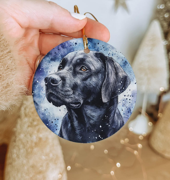 a hand holding a christmas ornament with a black dog on it