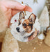 a hand holding a small ornament with a picture of a dog on it