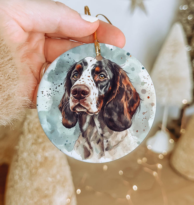 a hand holding a christmas ornament with a picture of a dog