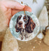 a hand holding a christmas ornament with a picture of a dog