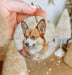 a hand holding a small ornament with a picture of a dog