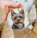 a hand holding a christmas ornament with a picture of a dog