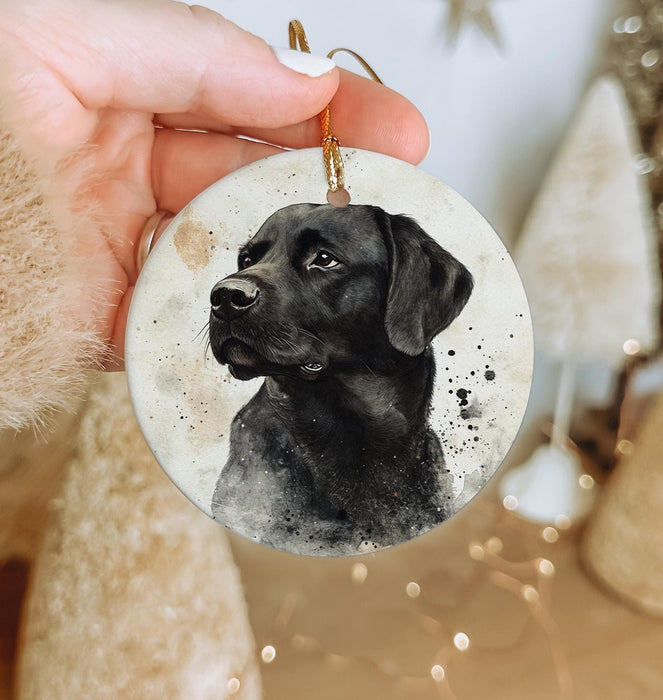 a hand holding a black dog ornament in front of a christmas tree