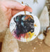 a hand holding a round ornament with a picture of a dog on it