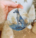 a hand holding a ceramic ornament with a dog on it