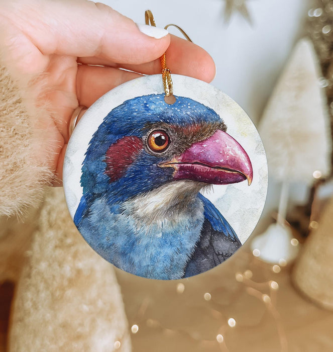 a hand holding a christmas ornament with a blue bird on it